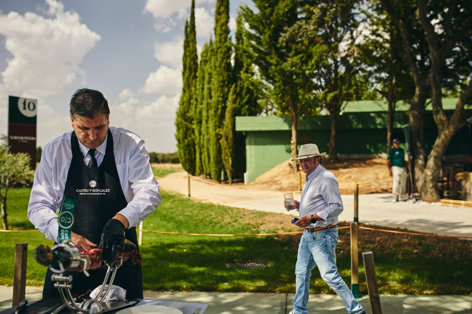 Cortador de jamón trabajando junto al cartel del hoyo 10