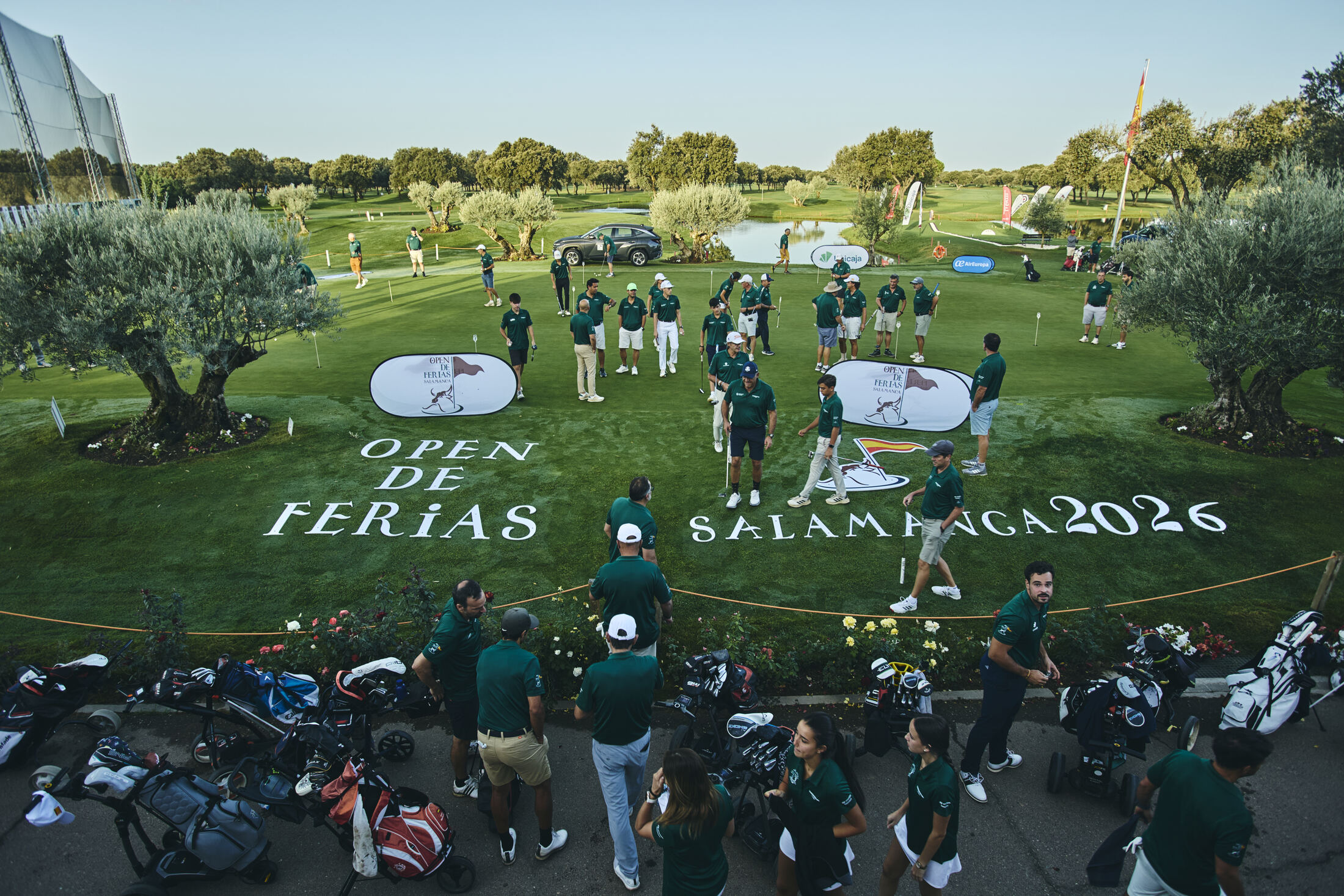 Jugadores del Open de Ferias en el campo de prácticas de La Valmuza, con el nombre del torneo escrito sobre el césped