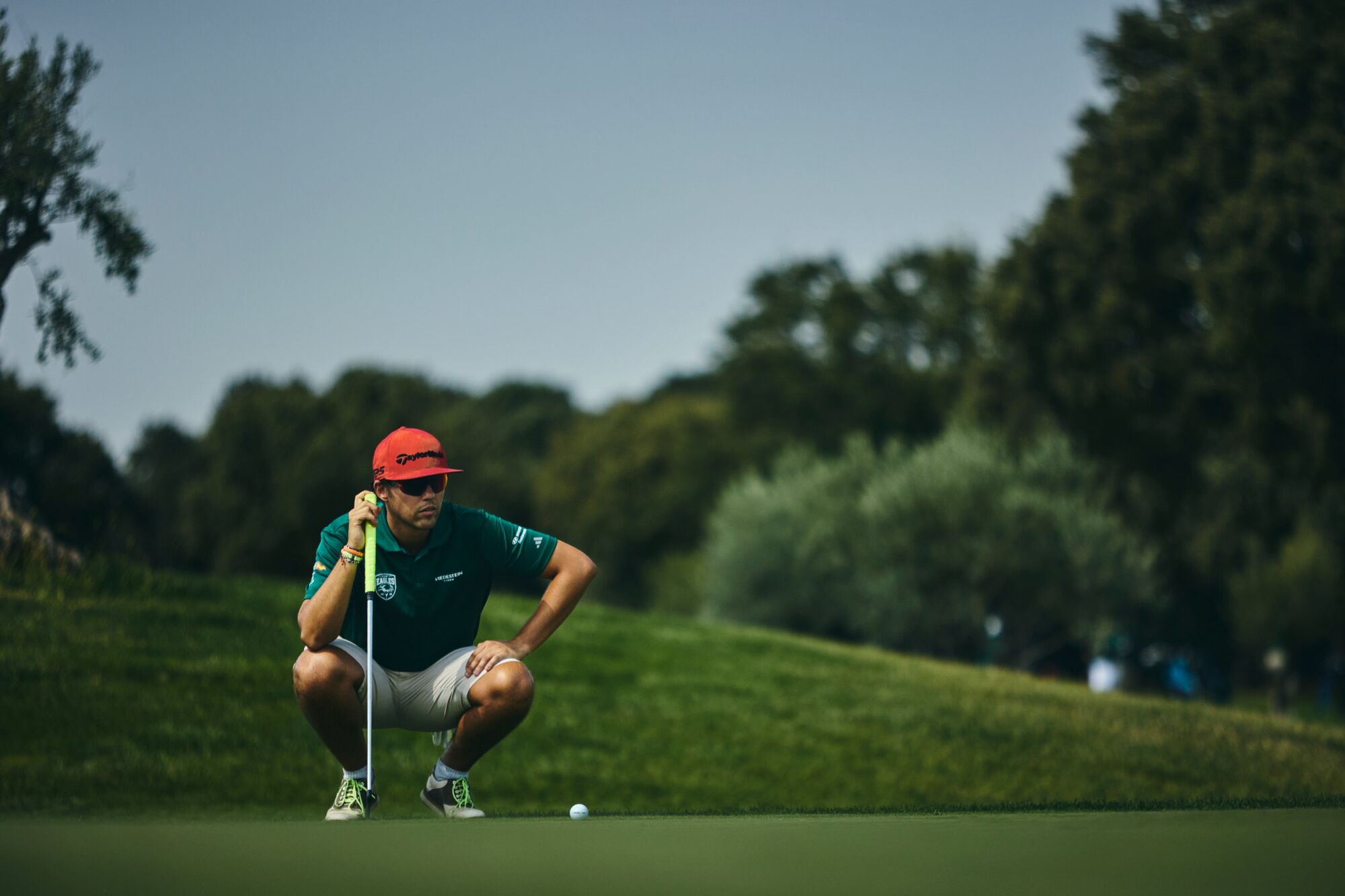 Jugador agachado leyendo la caída del putt sobre el green