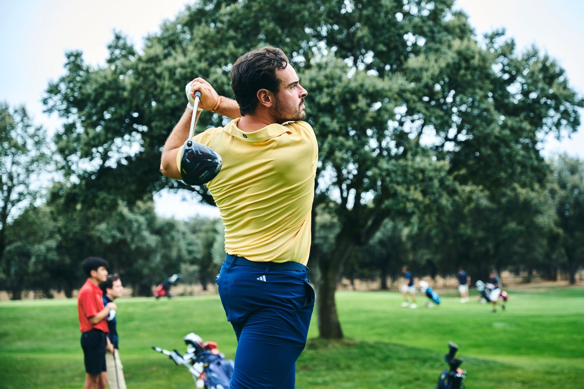 Jugador con polo amarillo terminando el swing con el driver